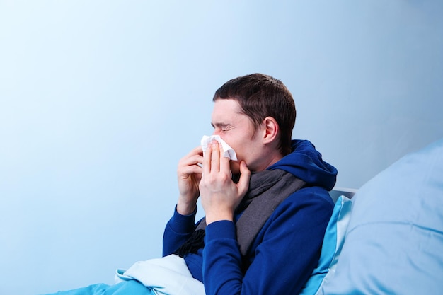 Photo of side of sick man with handkerchief sitting in bed