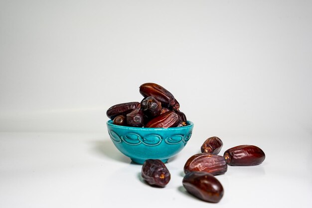 photo a small bowl of dates next to a handful on white background. high quality photo