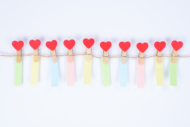 Photo photo of small clothespins in shape of hearts hanging on rope with small vertical colorful reminders isolated white background