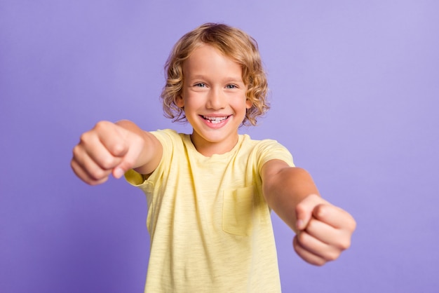 Photo of small positive boy imagine drive car wear yellow t-shirt isolated over purple color background