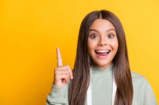 Photo of smart clever school girl wear casual grey outfit pointing empty space isolated yellow color background