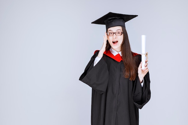 Foto di uno studente intelligente con gli occhiali che celebra la laurea con un diploma. foto di alta qualità