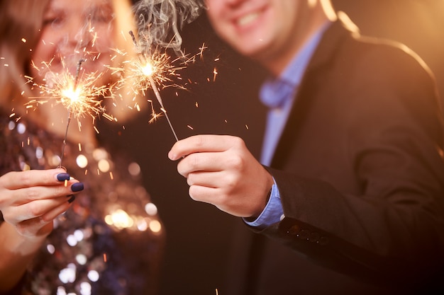 Photo of smiling couple with sparklers on black background