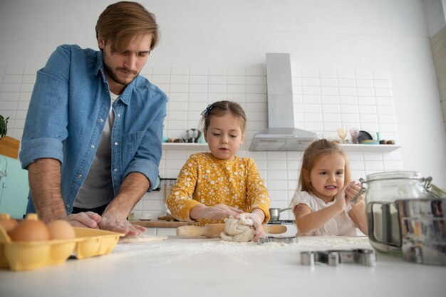 Photo of a smiling father and daughters baking in the kitchen and having fun.