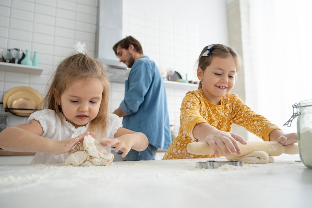 Photo of a smiling father and daughters baking in the kitchen and having fun.