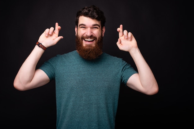 Photo of smiling man with crossed finger making a wish