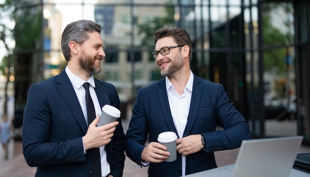 Photo of smiling trader men freelancing online having coffee two trader men freelancing online