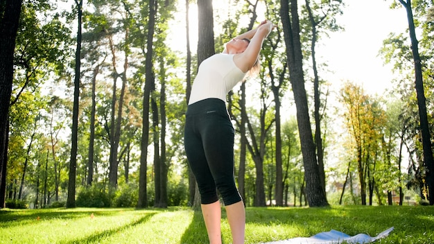 Photo of smiling woman doing yoga and fitness exercises. Middle aged people taking care of their health. Harmony of body and mind in nature