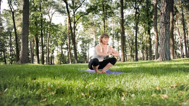 요가와 피트니스 운동을 하는 웃는 여성의 사진. 건강을 챙기는 중년들. 자연 속에서 몸과 마음의 조화