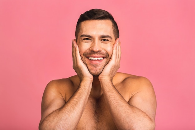 Photo of smiling young beautiful man standing naked. Man skincare concept in a bathroom.