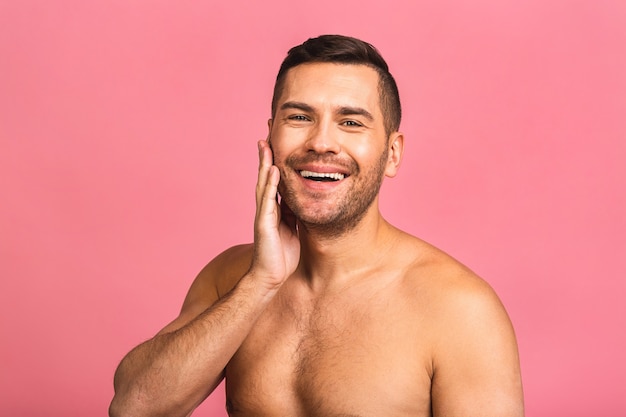 Photo of smiling young beautiful man standing naked. Mans skincare concept in a bathroom.