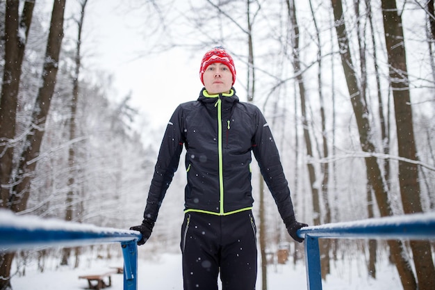 Foto dell'uomo sportivo sulla barra orizzontale in inverno nei boschi