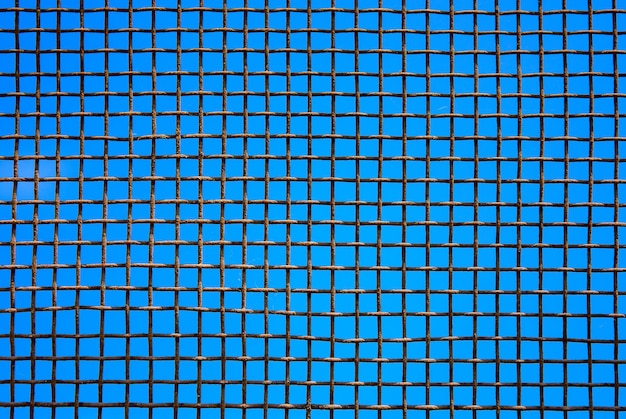 Photo of steel mesh wall on blue sky background