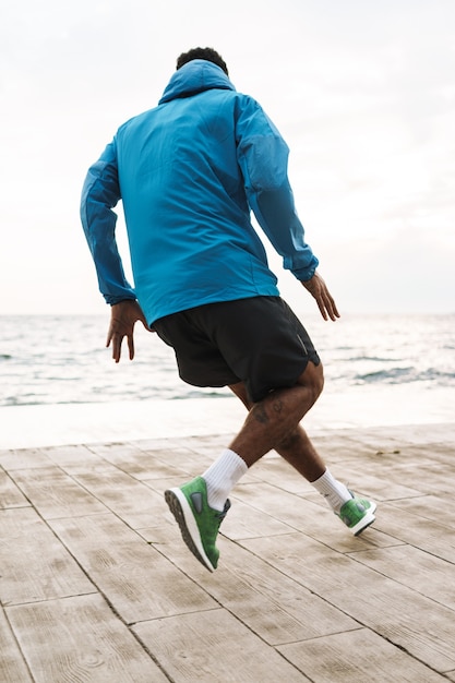 Photo photo of a strong handsome young african sports man runner outdoors at the beach sea running make exercises.