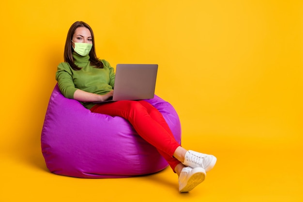 Photo of student lady sit cozy violet bean bag study notebook wear respirator sweater pants isolated yellow color background