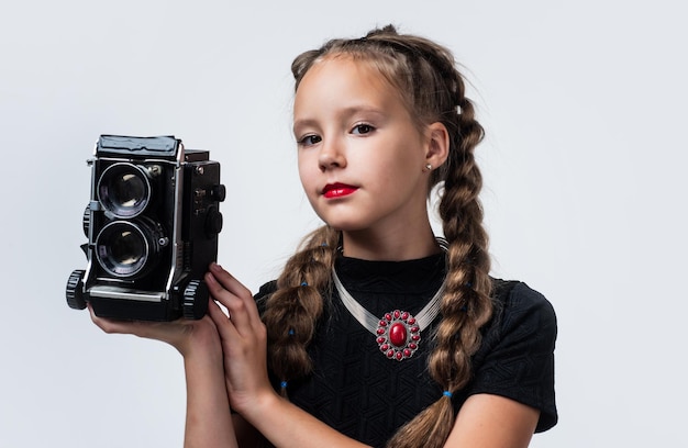 Photo studio cheerful girl with retro look isolated on white kid vintage fashion child take photo on retro camera beauty and fashion journalist or reporter photographing childhood happiness