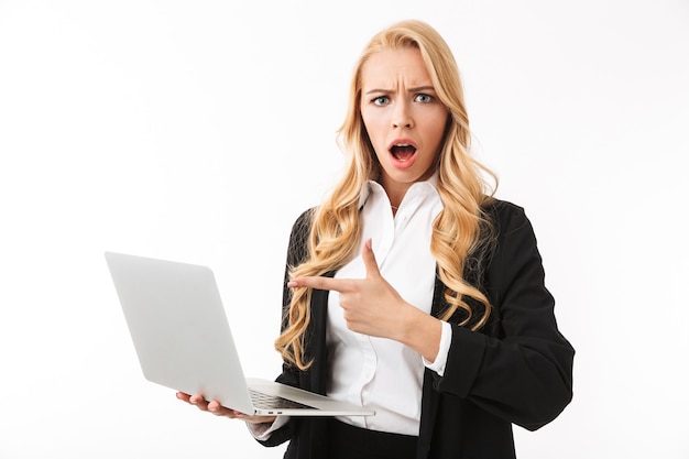 Photo of surprised businesswoman wearing office suit holding silver laptop, isolated