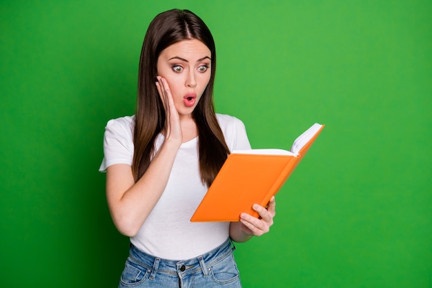 Photo of surprised cute brunette hair young lady look book wear white t-shirt isolated on green color background