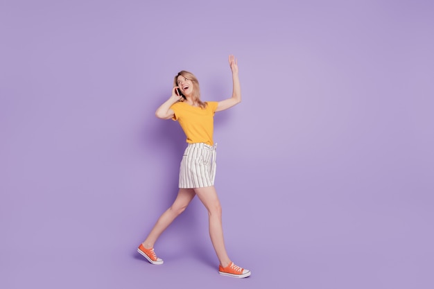 Photo of surprised girl talking on phone isolated on violet background