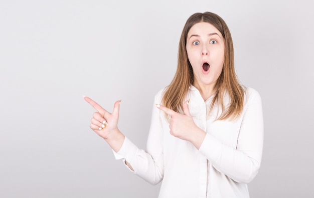 Photo of surprised woman points up, has shocked facial expression