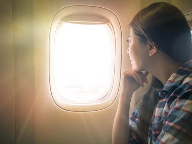 photo of sweet lady seriously view scenery of sunset sky. traveler sitting on the comfortable cabin seat looking out concept.