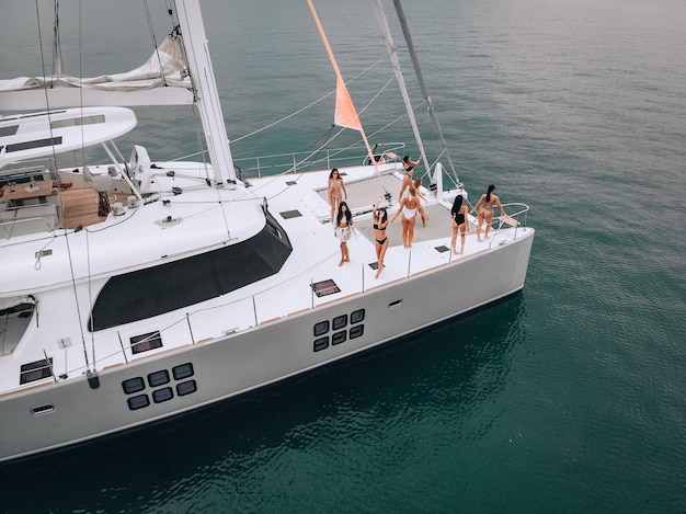 A photo taken by drone. luxury white yacht top view with some\
stunning young girls in swimwear. expensive vacations on the open\
seas. enjoying the tropical atmosphere. the concept of a heavenly\
place.