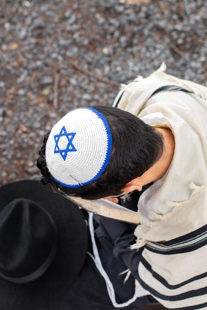 Photo taken from above of a Jewish man with kippah and taltit performing a religious prayer ritual