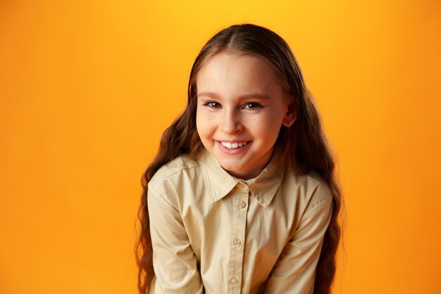 Photo of teen girl smiling portrait against yellow background in studio