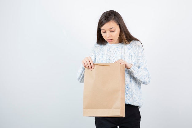 Photo of teen girl in sweater looking inside of craft bag.