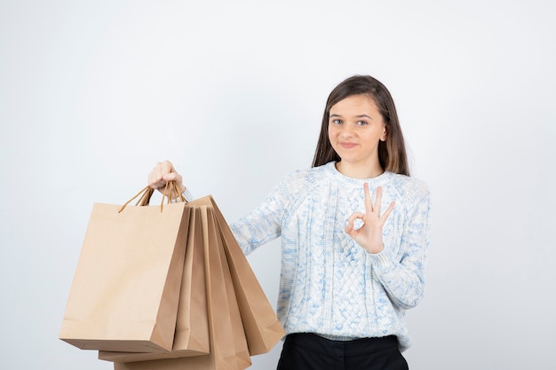 Photo of teen girl in sweater standing and holding paper bags