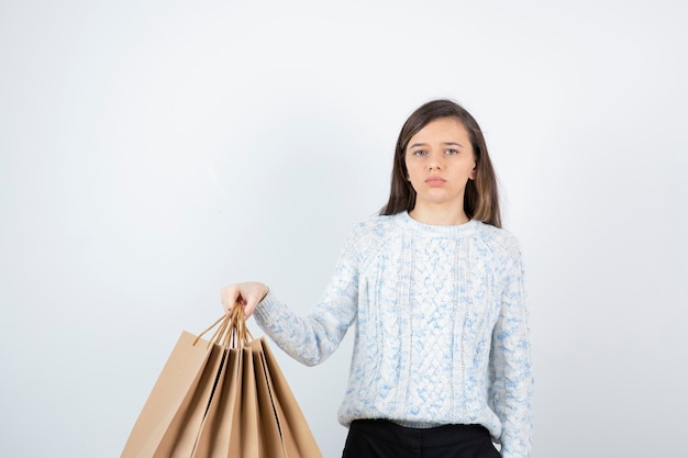 Photo of teen girl in sweater standing and holding paper bags