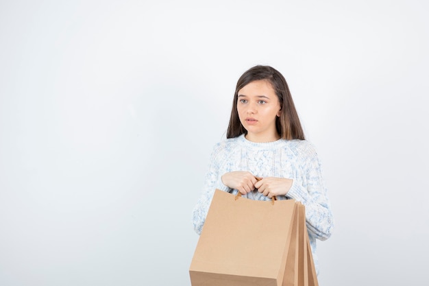 Photo of teen girl in sweater standing and holding paper bags