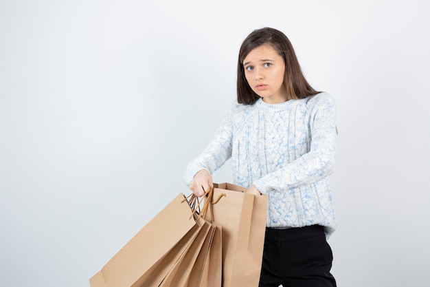 Photo of teen girl in sweater standing and holding paper bags