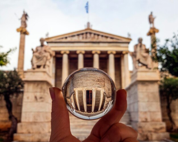 Foto foto attraverso un edificio a sfera di vetro della biblioteca nazionale di grecia con nuvole ad atene in grecia