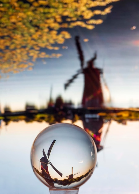 Фото через стеклянный шар Зеркальное отражение заката и ветряные мельницы канала в Нидерландах