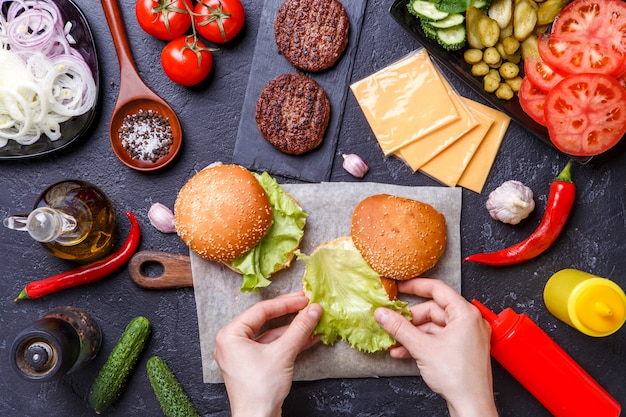 Photo on top of two hamburgers, human hands and ingredients