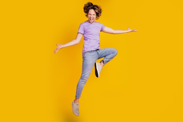 Photo of triumphant crazy man jump dance enjoy fun flight wear casual jeans clothes on yellow background