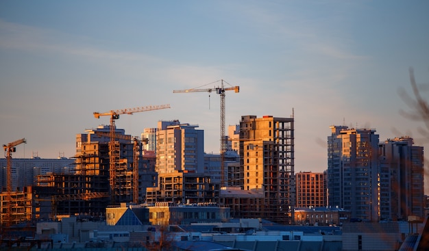 Photo of unfinished houses, cranes in evening