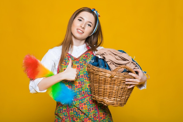 Photo of unhappy young housewife 20s carrying laundry basket with dirty clothes isolated