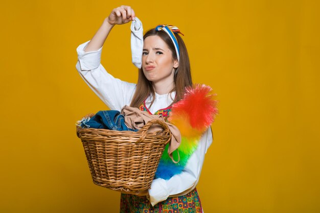 Photo of unhappy young housewife 20s carrying laundry basket with dirty clothes isolated