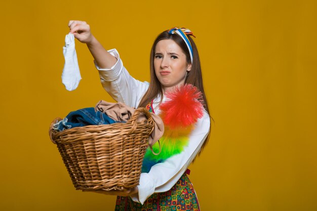 Photo of unhappy young housewife 20s carrying laundry basket with dirty clothes isolated