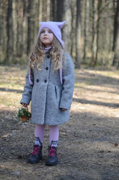 Photo of vintage dressed girl playing with flower basket in the forest