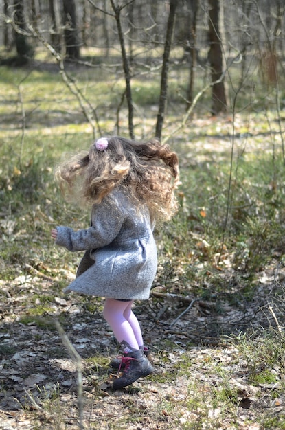 森で遊ぶビンテージ スタイルの服を着た少女の写真