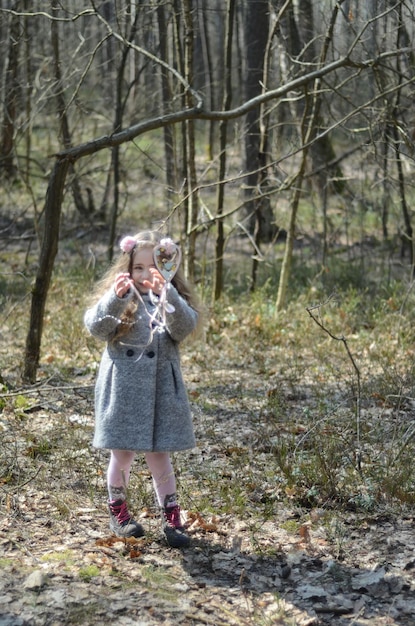 Фото одетой в винтажном стиле маленькой девочки, играющей в лесу