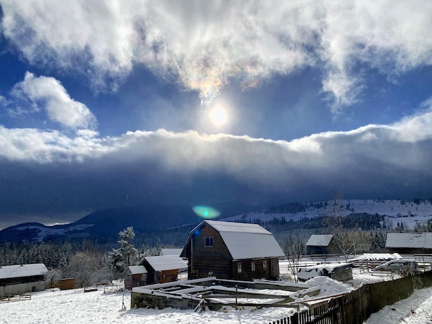 Photo winter view of the houses in the mountains and the bright sun