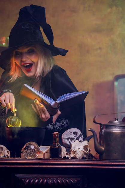 Photo of witch reading spell pumpkin in hand