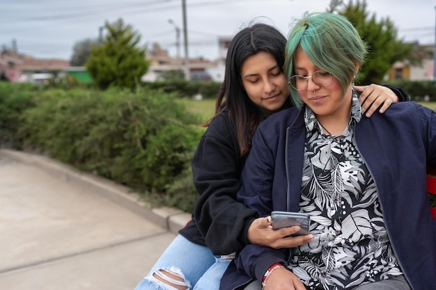 Photo with copy space of a lesbian couple using the mobile together in a bench