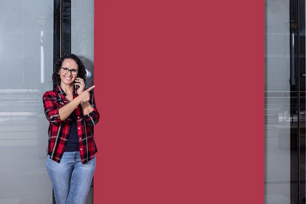 Photo with copy space of a woman talking with the mobile while pointing to a banner in a window shop