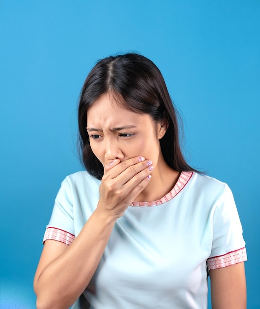 photo a woman coughing and covering her mouth with her hand on blue background