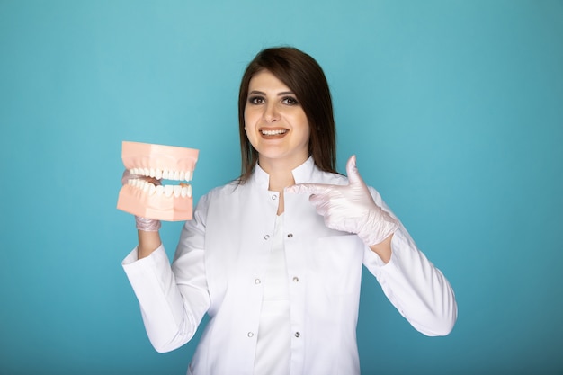 Photo of woman dentist standing isolated at the blue background.